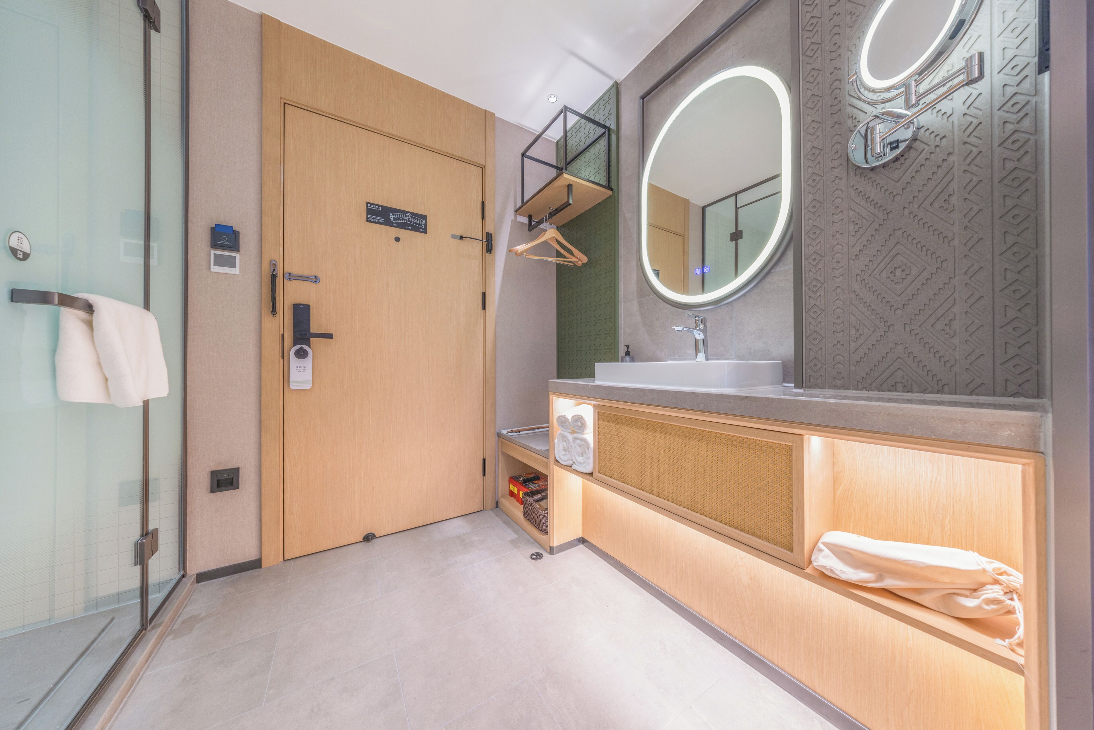 A modern bathroom with a glass shower enclosure, a wooden vanity with a mirror, and a towel rack.