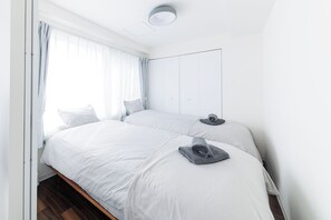 A modern bedroom with two beds, a large window with sheer curtains, and a minimalist design. - RUBY 501 (Otaru)