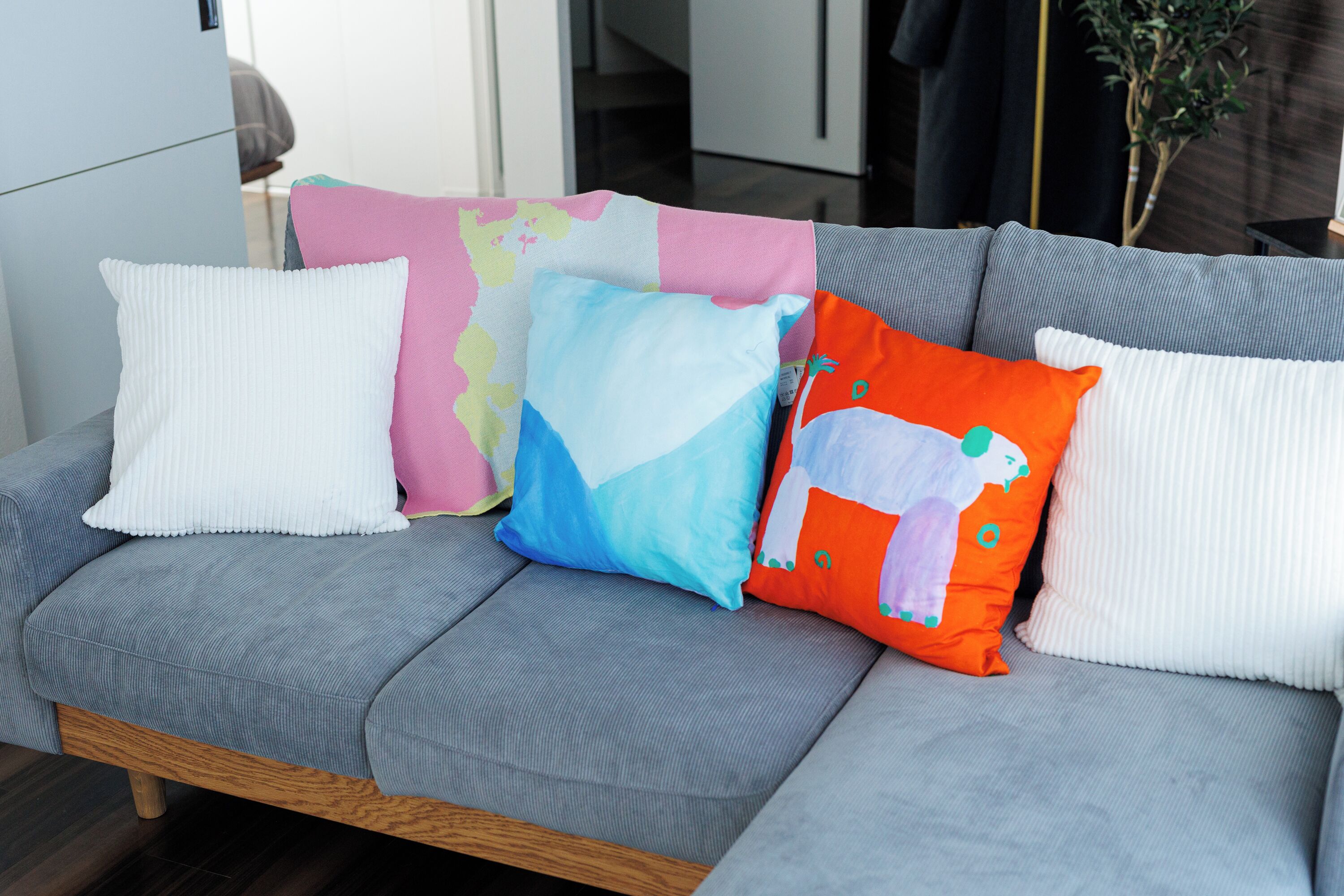 Un sofá gris con cuatro cojines de colores y diversos diseños.