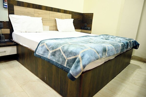 Una cama bien hecha con sábanas blancas y una colcha azul estampada.