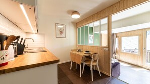 Eine kompakte Küche mit Holzarbeitsplatte, ein Essbereich mit Tisch und Stühlen sowie ein großes Fenster für natürliches Licht.