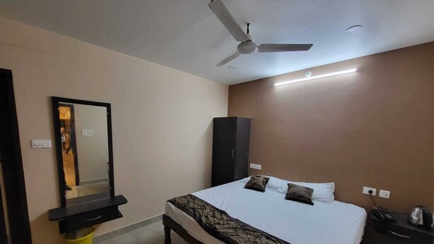 Quarto com uma cama, ventoinha no teto, guarda-roupa e espelho.