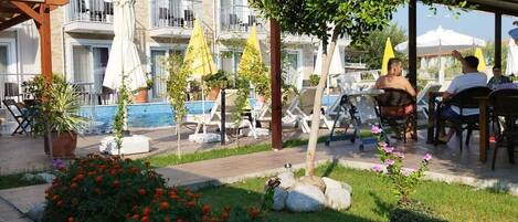 A hotel courtyard with a swimming pool, lounge chairs, and a garden area with flowers and rocks.