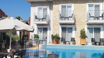 Un hotel con piscina, mobiliario exterior y balcones.
