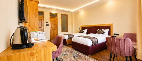 Une chambre d’hôtel avec un bureau en bois, deux lits, une télévision et un tapis à motifs.