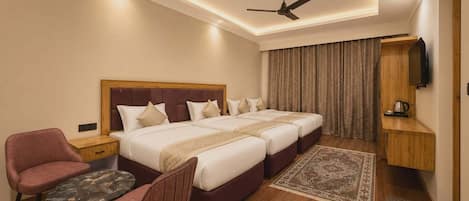 Une chambre d’hôtel comprenant un lit, deux chaises, une petite table, un ventilateur de plafond, une télévision et une armoire en bois.