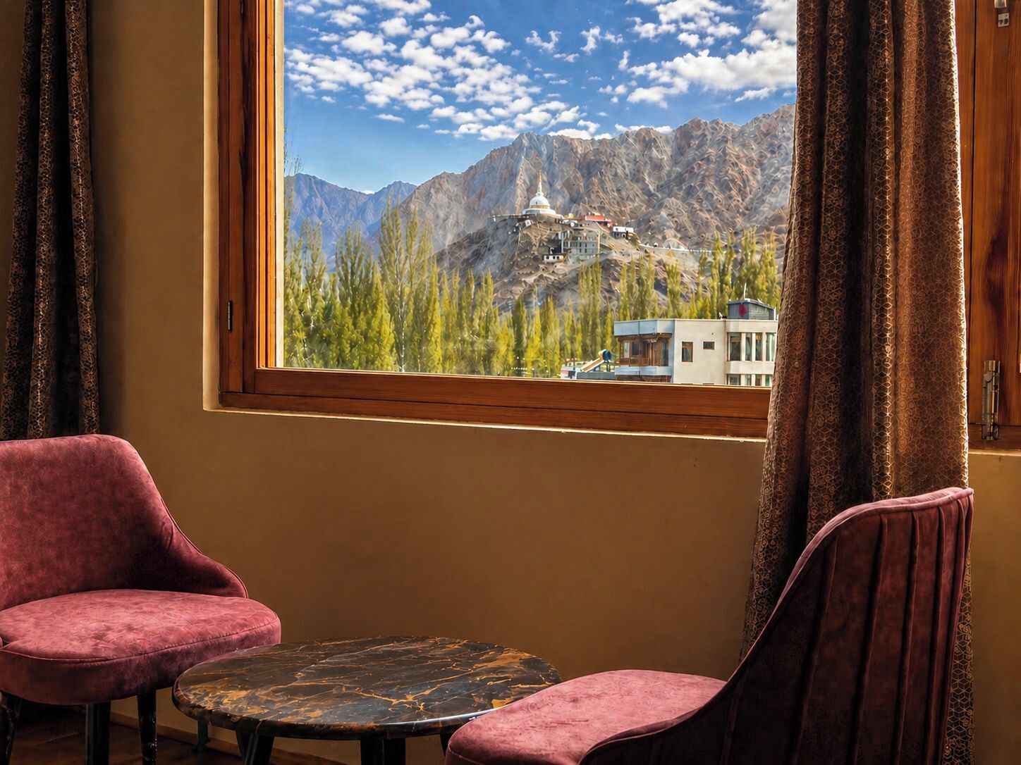 A room with a large window, two chairs, and a small table.