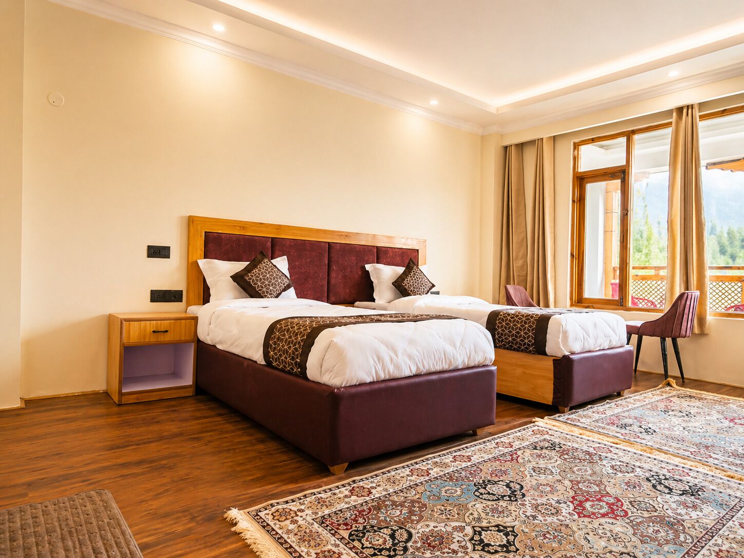 A bedroom with two beds, a wooden headboard, a nightstand, a chair, and a large window with curtains.