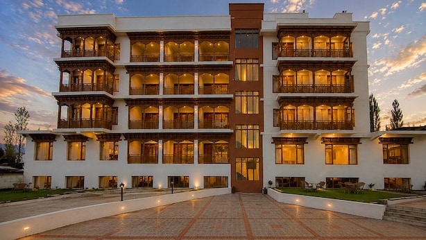 Un hôtel à plusieurs étages, doté de balcons, d’une entrée principale et d’une cour dallée.