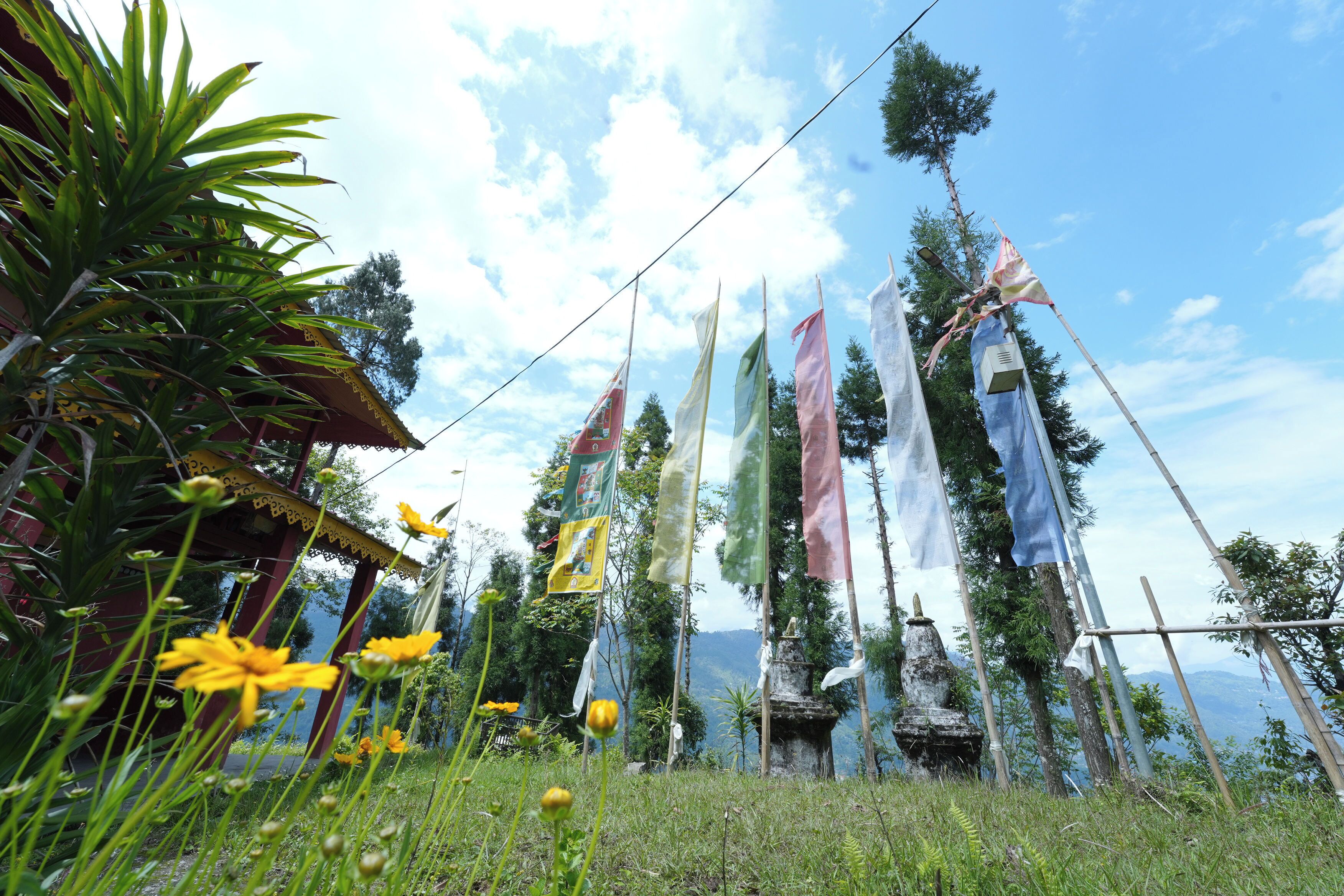 A traditional structure with flags, surrounded by greenery and a clear sky.