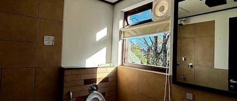 A bathroom with a toilet, sink, and window with a view.