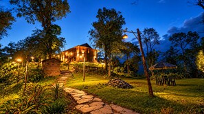 A house with a stone staircase leading up to it, surrounded by trees and a grassy area. - RedPanda Jungle Camp (Gyalshing)