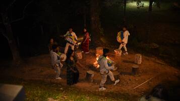 A group of people gathered around a campfire in an outdoor setting.