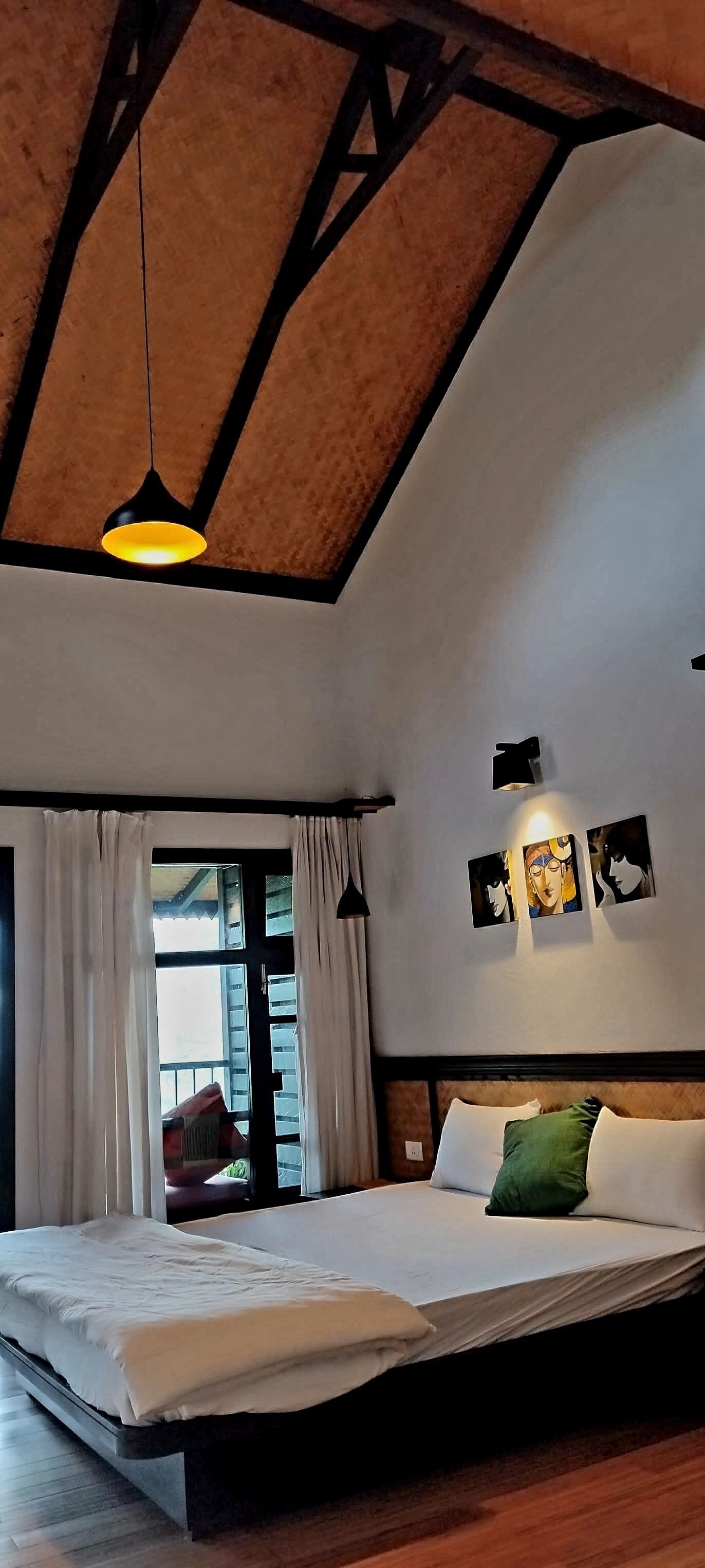 Un dormitorio con una cama grande, vigas de madera en el techo, una ventana con cortinas y una obra de arte colgada en la pared.