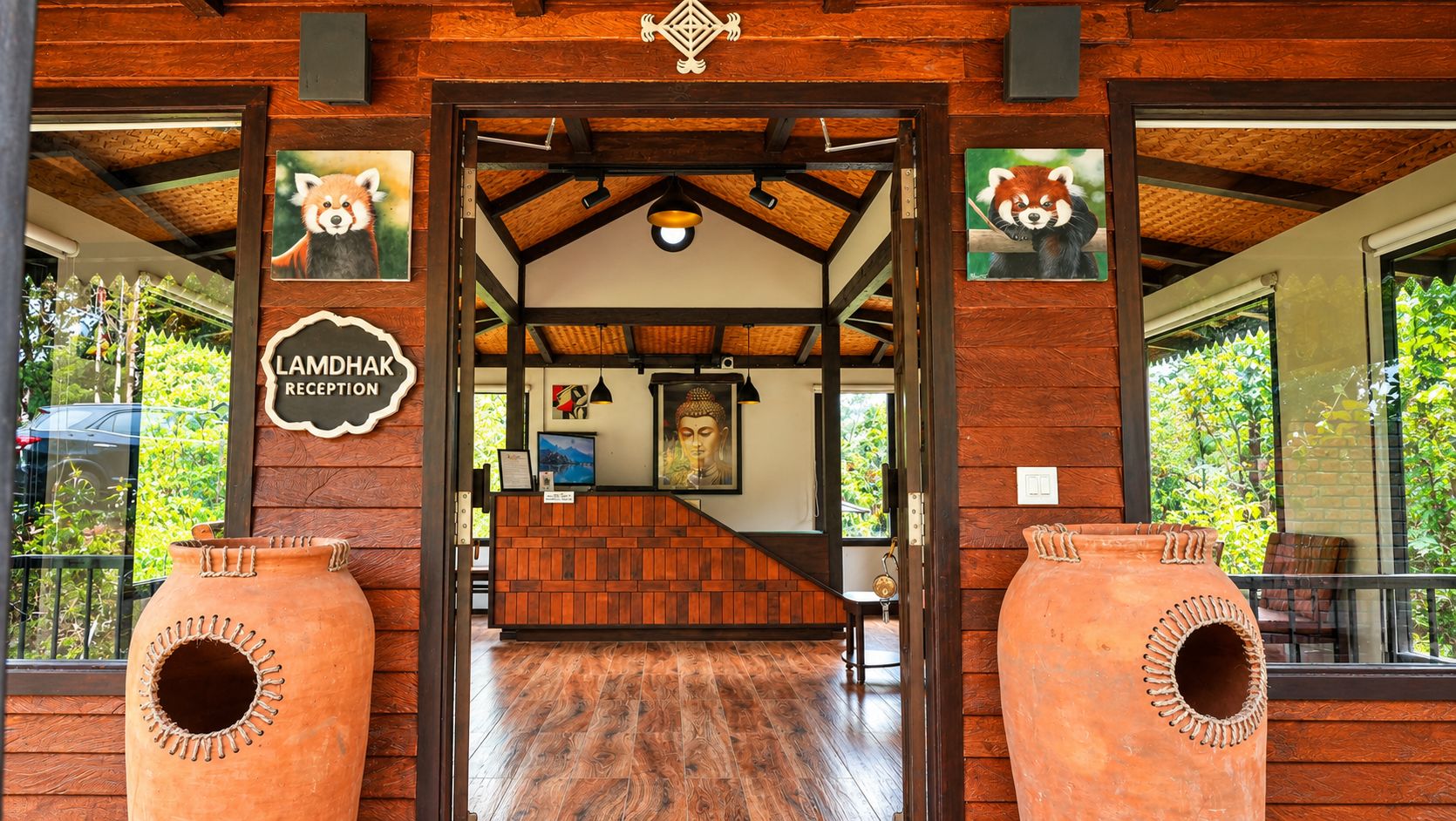 A reception area with a wooden interior, a Buddha statue, and terracotta pots.