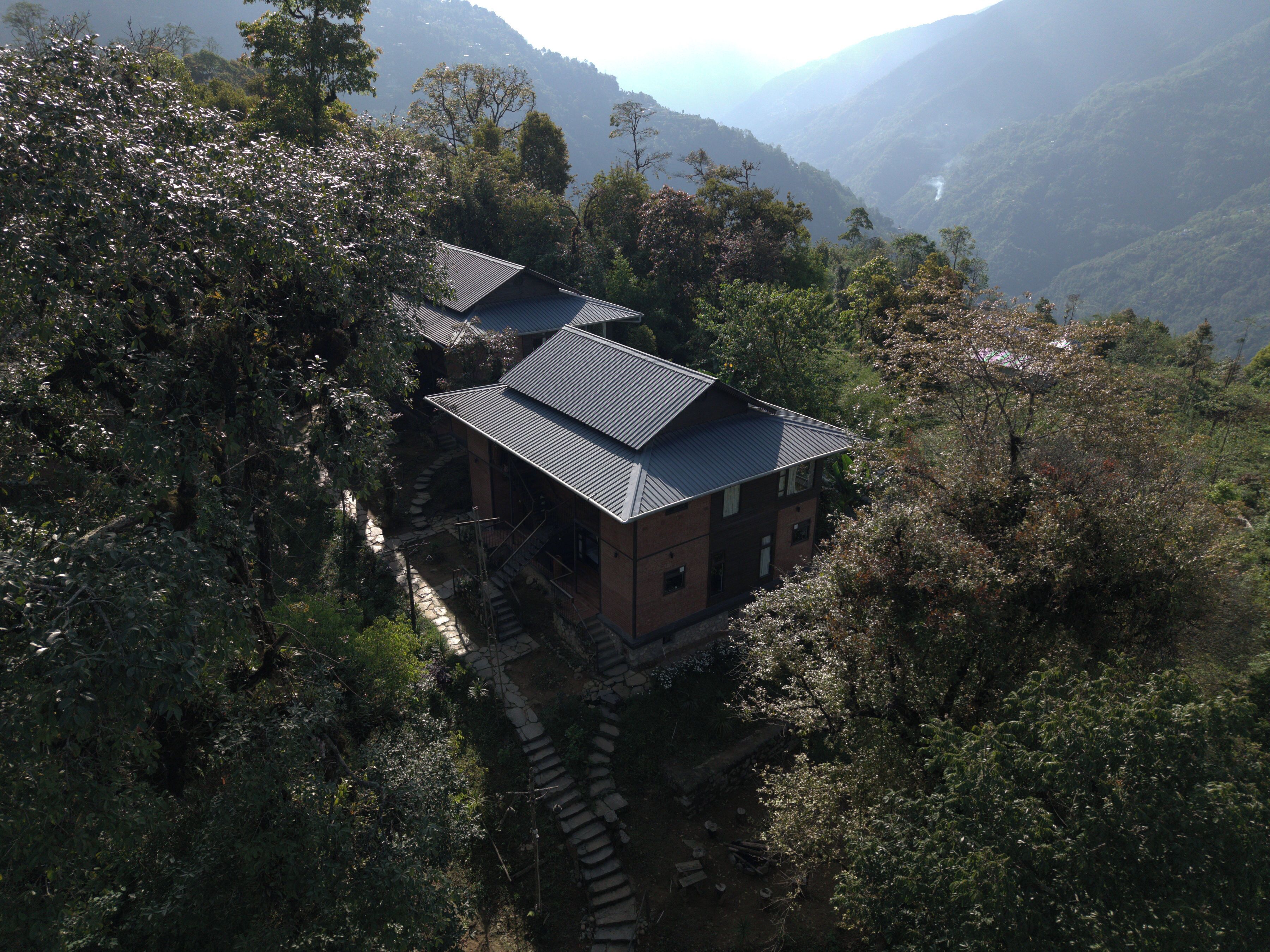 Una casa tradicional japonesa con techo inclinado, rodeada de un bosque denso y montañas.