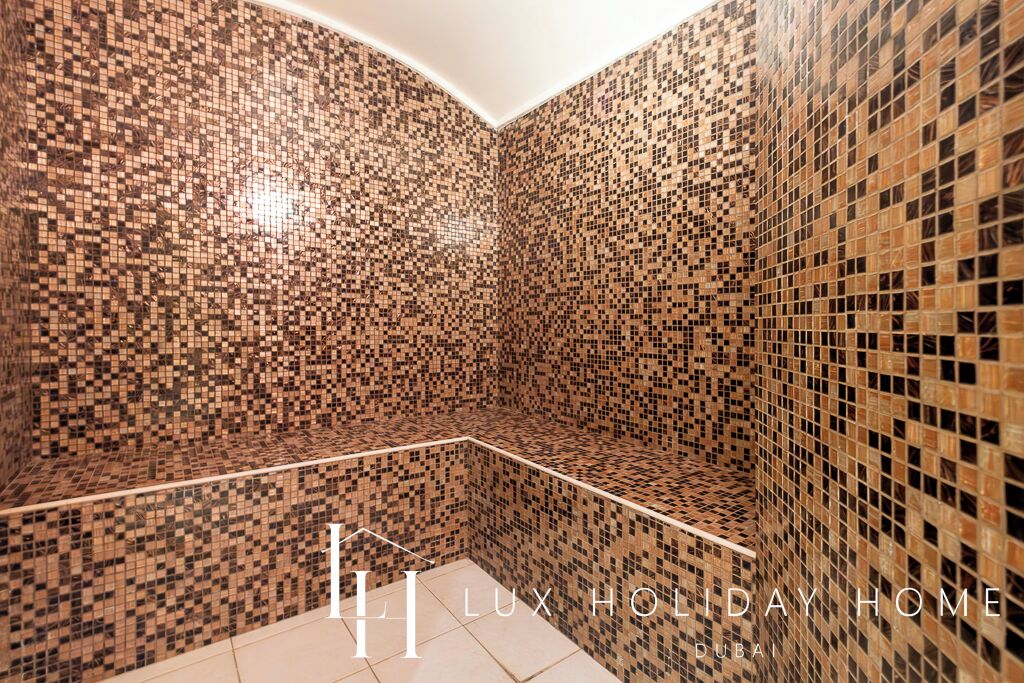 A corner bathroom with mosaic tile walls and a tiled floor.