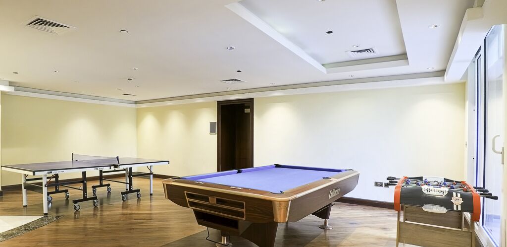 A room with a pool table, foosball table, and ping pong table.