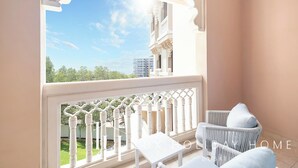 Un balcon avec des balustrades blanches, une table blanche et deux chaises en osier avec des coussins.
