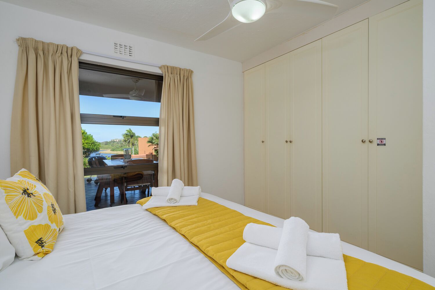 A hotel room with a bed, a desk, and a view of the outdoors.