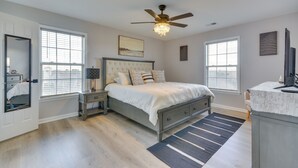 A bedroom with a large bed, a ceiling fan, and two windows. - Easy Access to Dtwn: High Point Condo (High Point)
