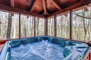 Un jacuzzi en una cabaña de madera con vista al bosque.