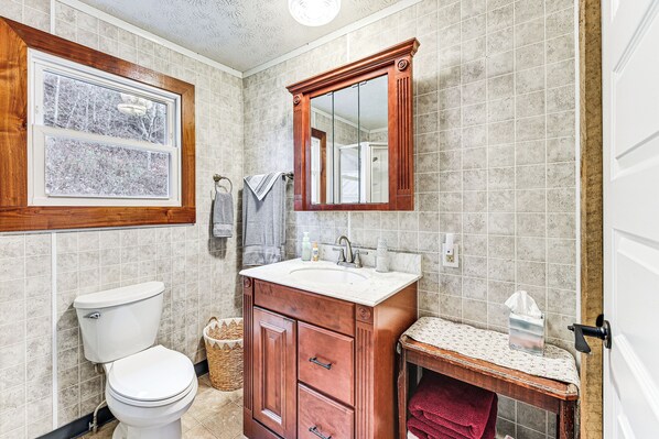 A bathroom with a toilet, sink, and mirror. - On 220 Acres! Hot Tub Haven in West Liberty (West Liberty)