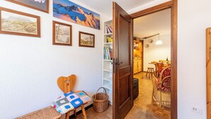 Une pièce chaleureuse avec une chaise en bois, une petite table et un mur décoré de tableaux encadrés.