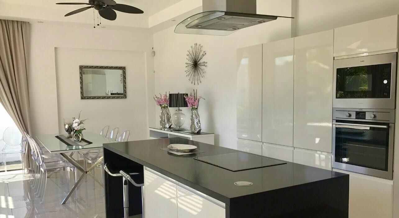 A modern kitchen with a central island, stainless steel appliances, and a ceiling fan.