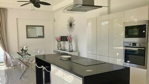 A modern kitchen with a central island, stainless steel appliances, and a ceiling fan.
