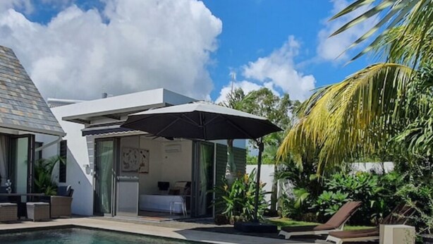 A modern house with a swimming pool, outdoor seating, and lush greenery.