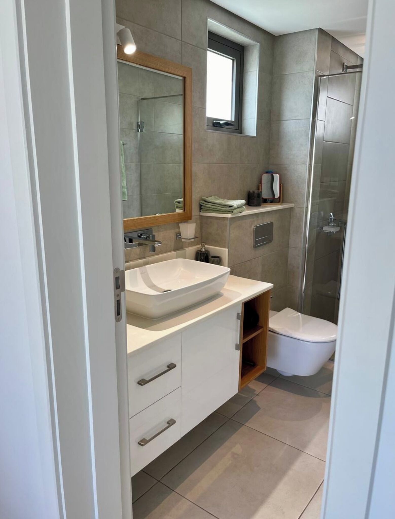 A modern bathroom with a large sink, mirror, and a walk-in shower.