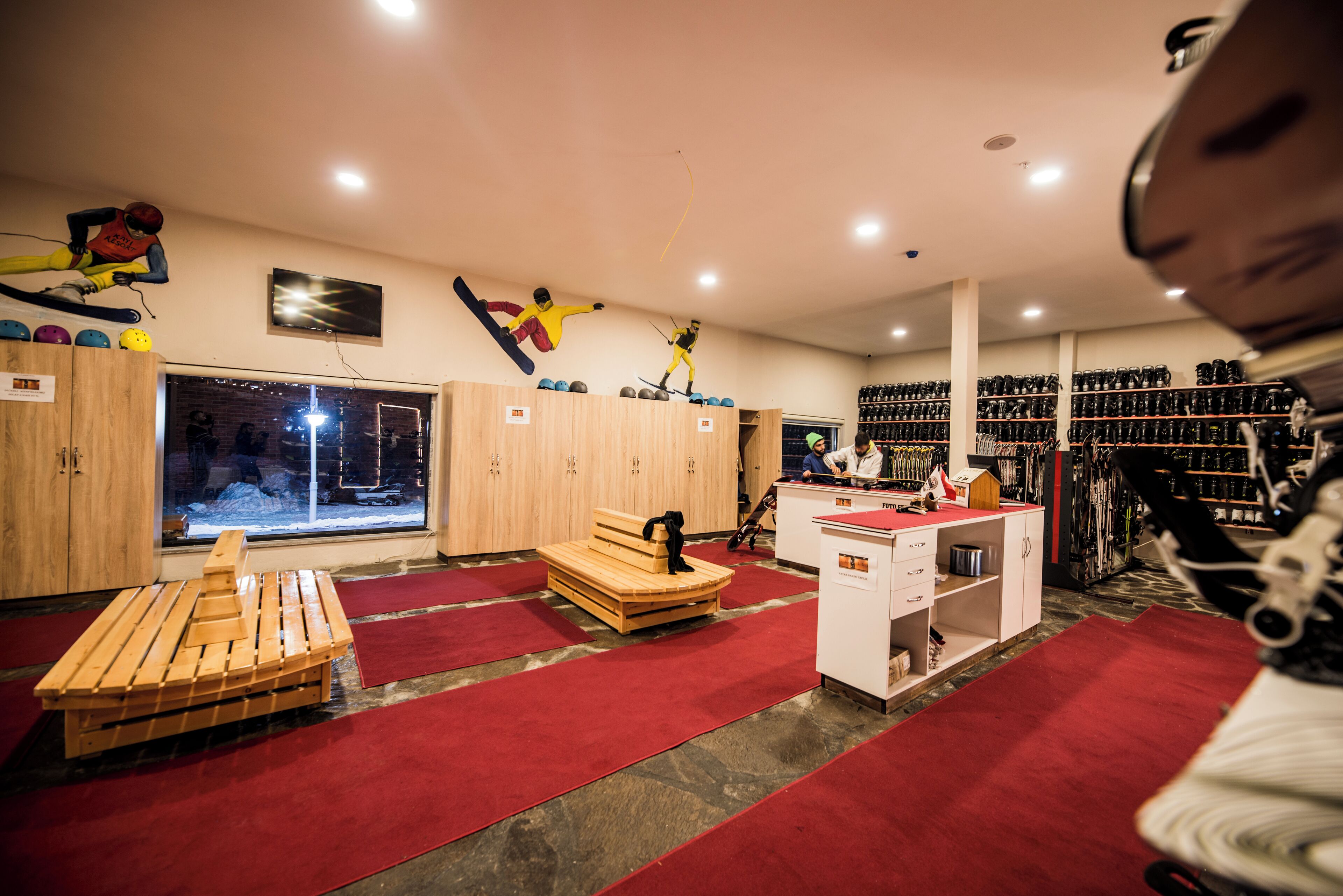 A ski rental facility with wooden benches, a ski lift, and a wall of skis.