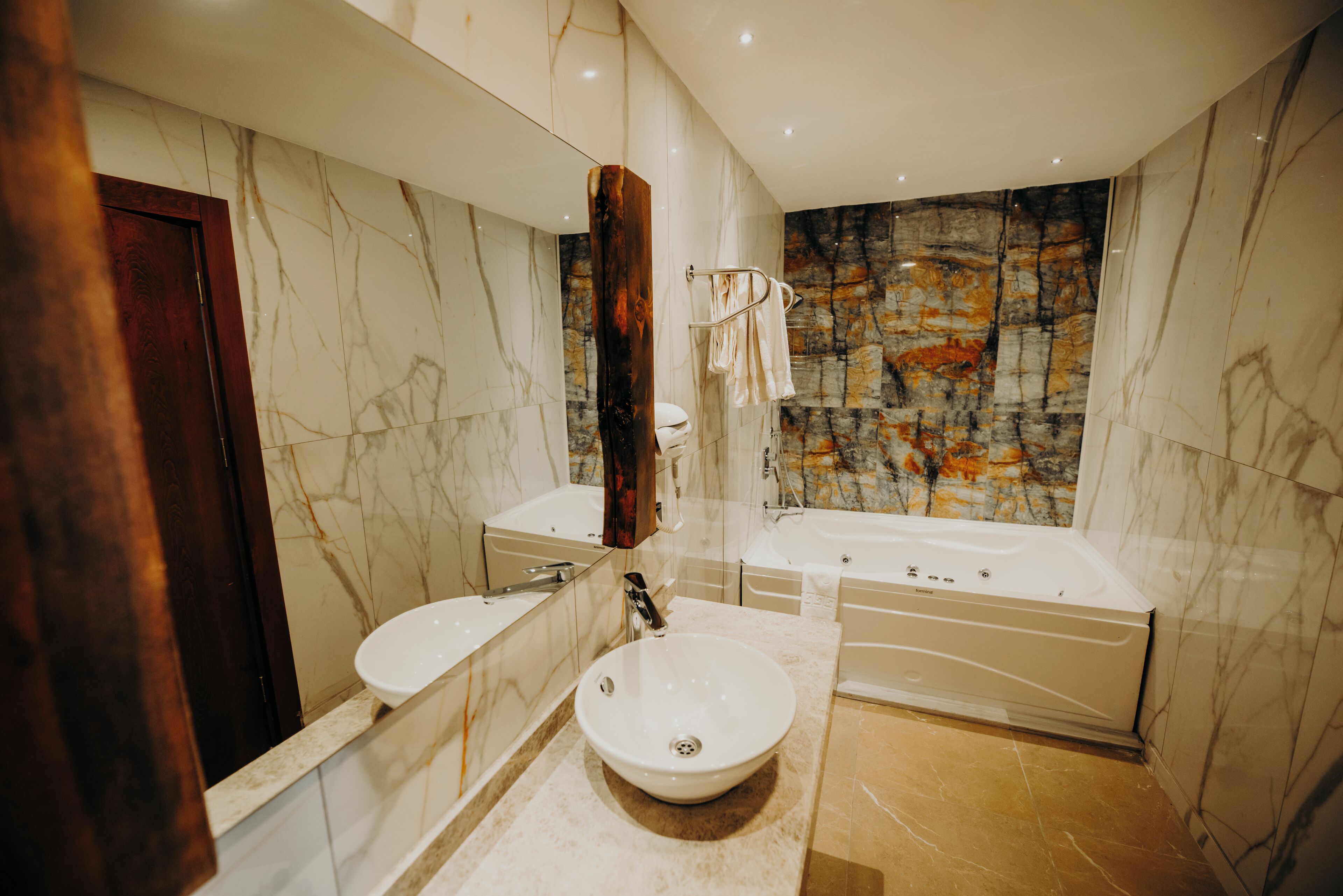 Une salle de bain moderne avec un meuble-lavabo en marbre, un évier, une baignoire et un grand miroir.