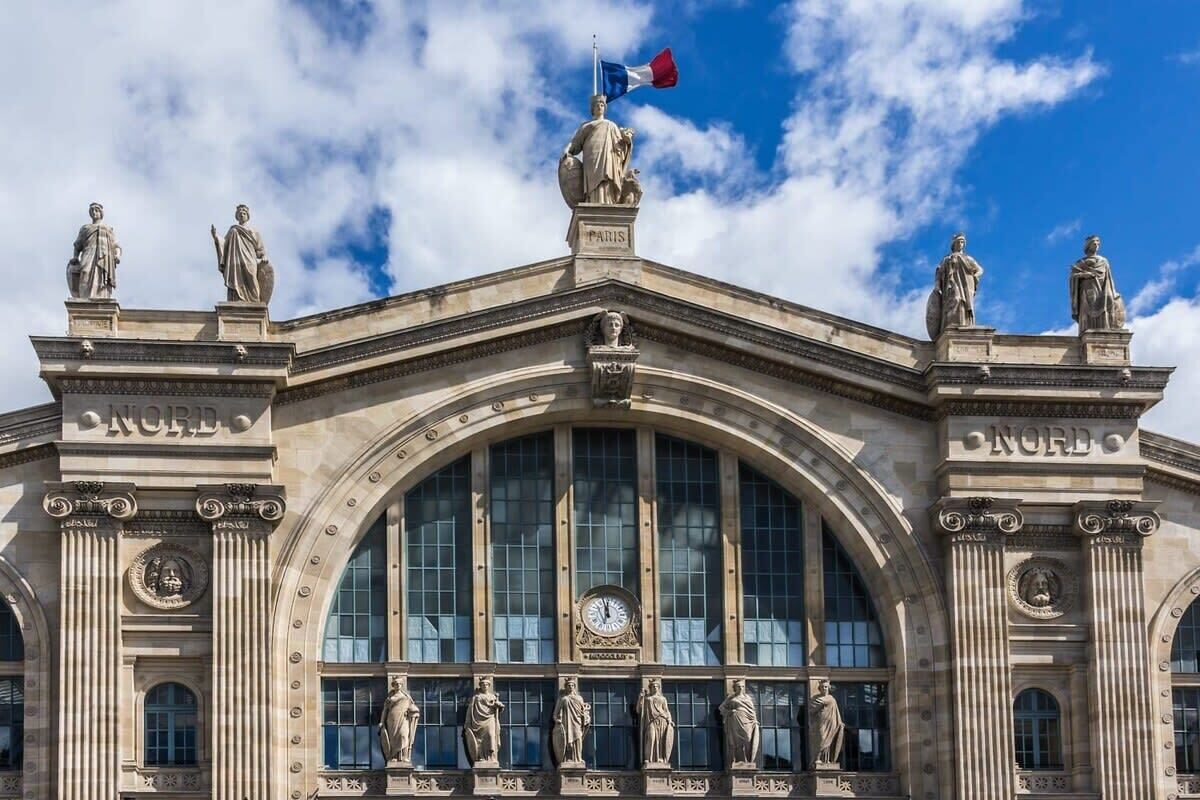 Ein prachtvolles Gebäude mit klassischer Architektur, das ein großes Rundbogenfenster und Statuen an der Fassade zeigt.