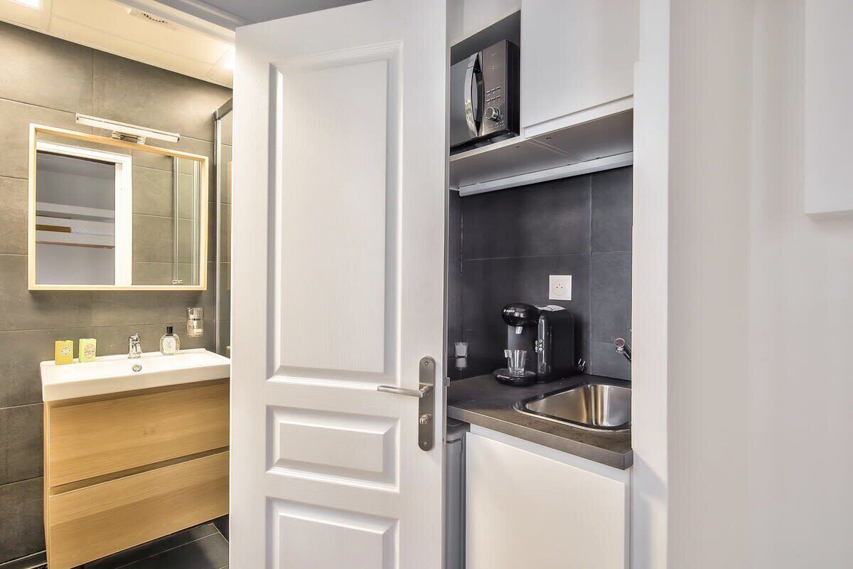 Un baño moderno con tocador blanco, espejo y zona de ducha.