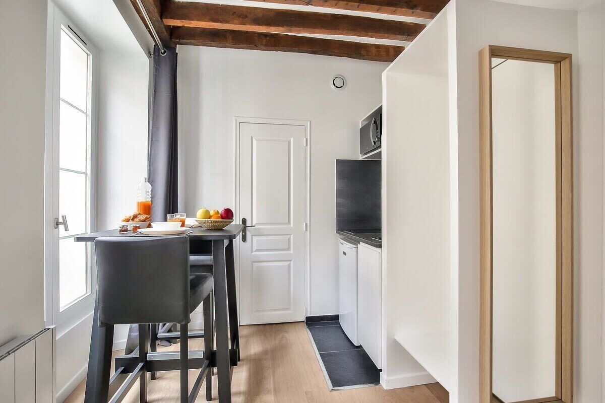 Een compacte keuken met een eethoek, een magnetron en een deur naar een andere kamer.