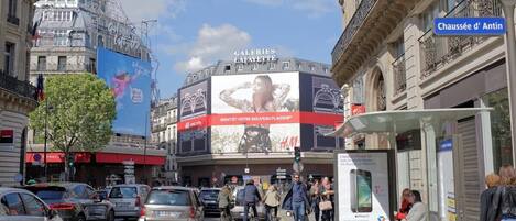 A busy urban street with a large billboard advertising a new fashion brand.