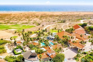 Ein Luftbild eines Resorts mit Schwimmbad, Palmen und Strand.