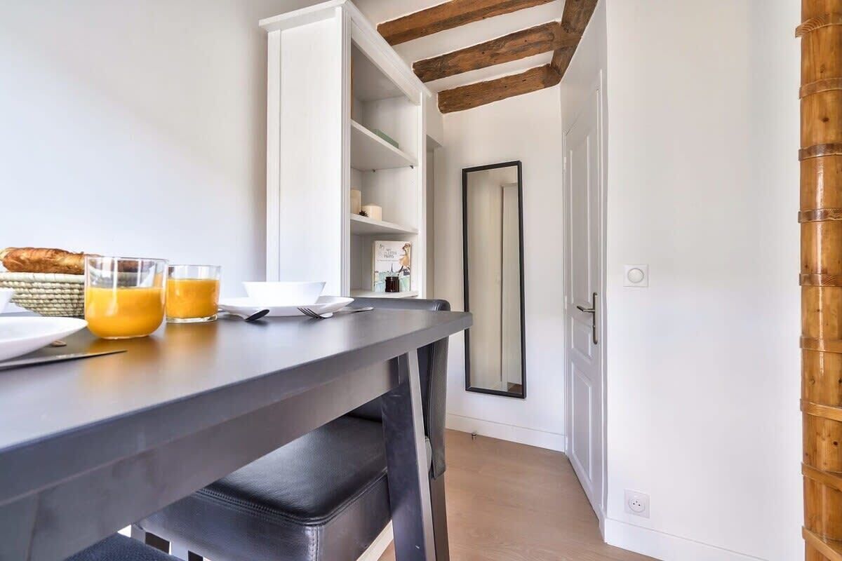 A modern kitchen with a dark countertop, a white cabinet, and a wooden beam ceiling.