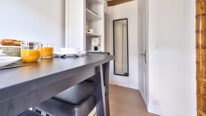 Une cuisine moderne avec un plan de travail foncé, des placards blancs et un plafond avec une poutre en bois.