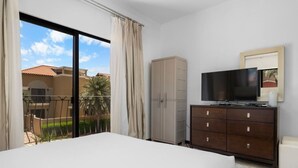 A hotel room with a balcony, a television, a wardrobe, and a bed. - Exquisite Poolside Living in Diamante 165 by Bocobay (Noord)