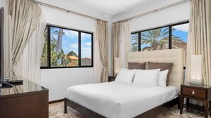 A hotel room with a bed, bedside tables, a desk, and curtains. - Exquisite Poolside Living in Diamante 165 by Bocobay (Noord)