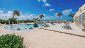 A resort pool area with lounge chairs, a swimming pool, and palm trees. - Exquisite Poolside Living in Diamante 165 by Bocobay (Noord)