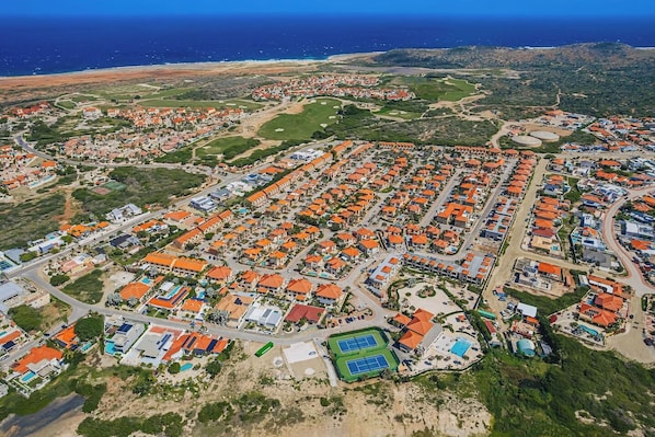 Vista aérea de una zona residencial costera con casas, carreteras y una playa.
