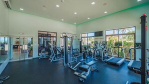 A gym with exercise equipment, large windows, and a view of greenery outside. - Exquisite Poolside Living in Diamante 165 by Bocobay (Noord)