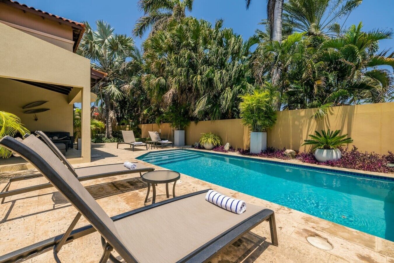 A pool area with lounge chairs and a covered seating area.
