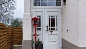 Una puerta blanca con un letrero rojo, una valla de madera y una planta en maceta.