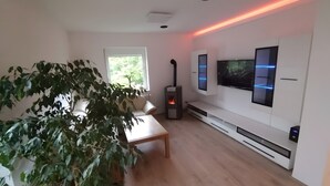 A modern living room with a fireplace, a sofa, a coffee table, and a TV mounted on the wall. - Holiday Home 'Ferienhaus Kesper' with Mountain View, Private Terrace & Wi-Fi (Schottwien)