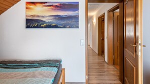 Un dormitorio con cama, un pasillo con puertas de madera y un cuadro de paisaje en la pared.